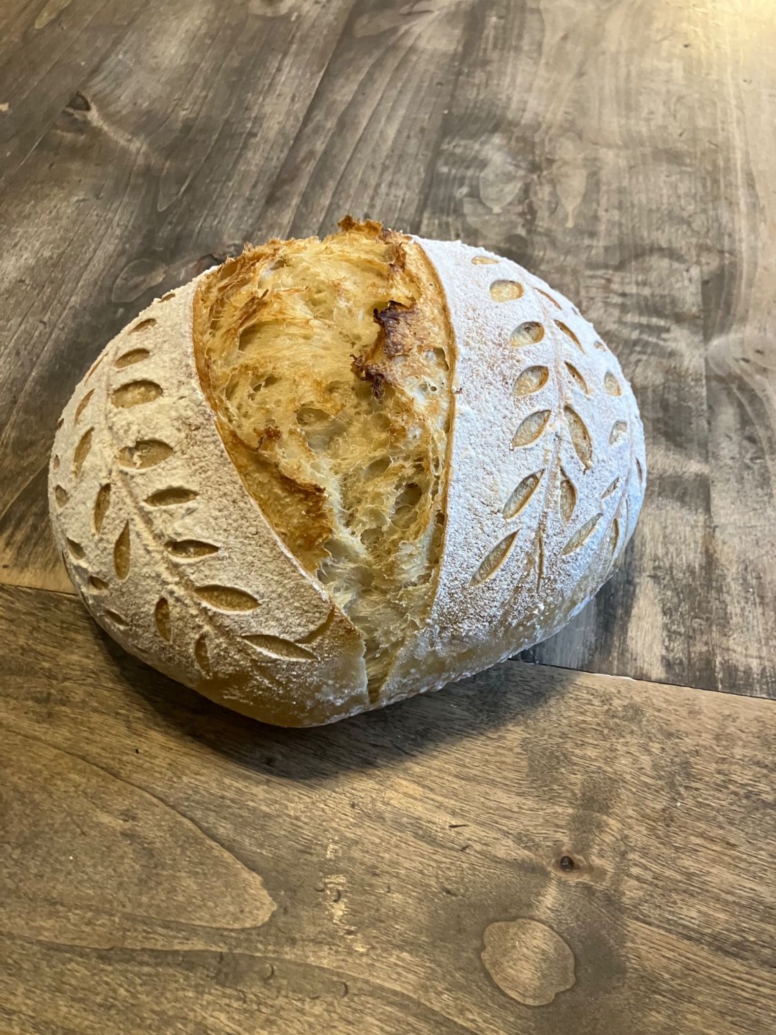 White sourdough artisan loaf scored with a wheat-leaf pattern
