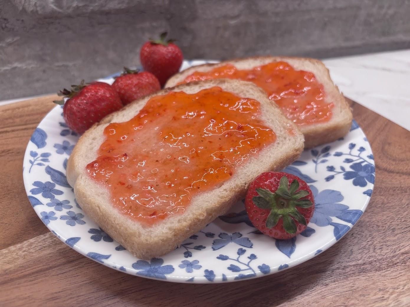 Strawberry freezer jam spread on fresh white bread with berries